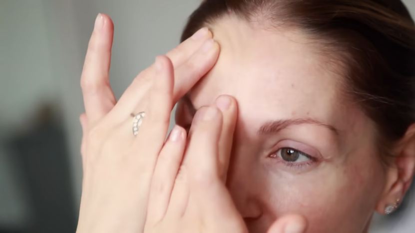 A Woman Gently Massaging Her Forehead with Her Fingers to Reduce Wrinkles and Improve Skin Elasticity