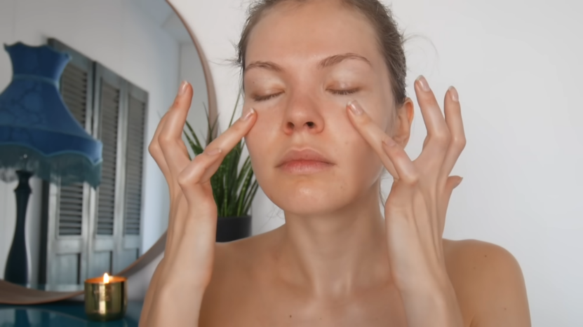 A Woman Performing a Gentle Face Massage with Her Fingers on Her Cheeks and Under Her Eyes in A Calm, Softly Lit Room